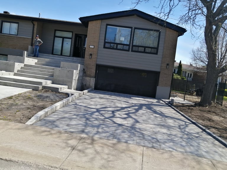 Modern two-story house with brown and gray exterior, black garage door, and concrete driveway under construction